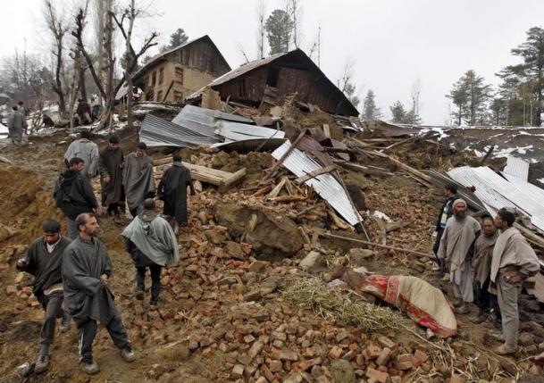 Police stand amidst the rubble after a hillside collapsed onto a house at Laden
