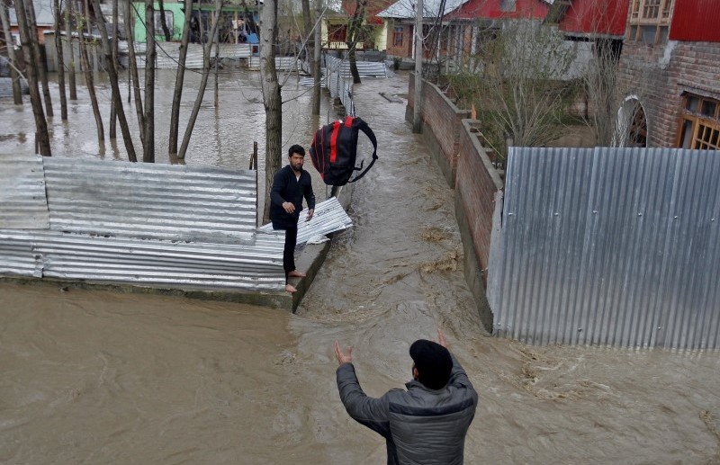 A man throws his belongings towards another to be moved to a safer place at a flooded neighbourhood after incessant rains in Srinagar